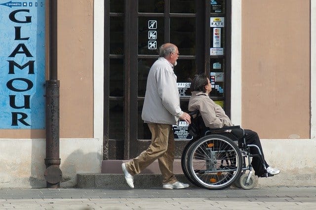 איש סוחב אישה על כסא גלגלים